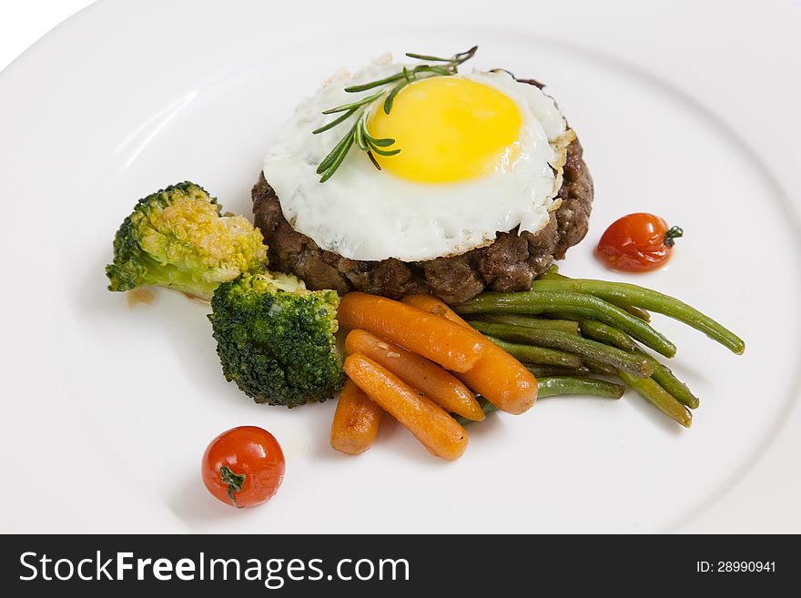 Patty, cooked vegetables and fried eggs