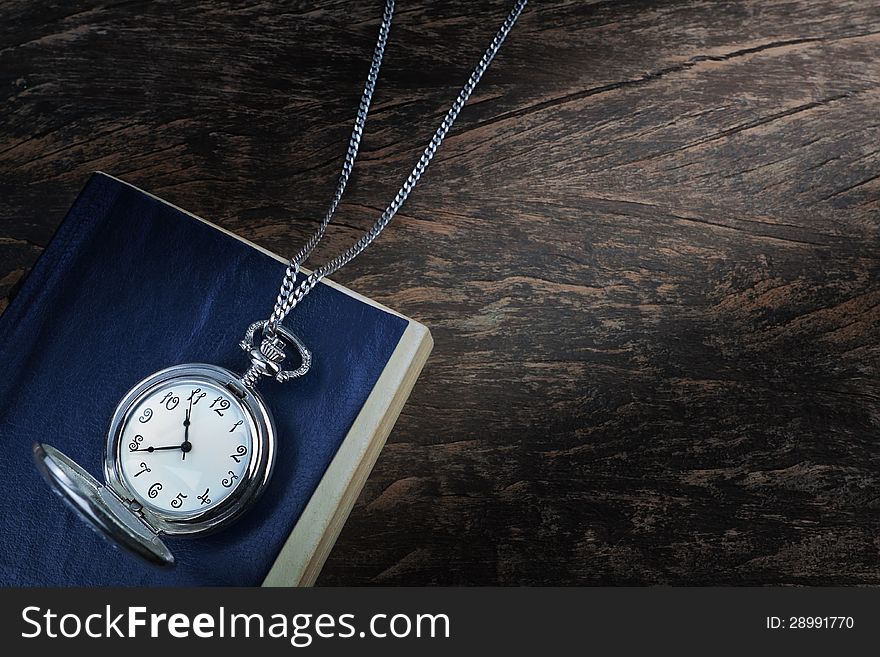 Pocket watch on an old book, a notebook on wooden texture. Concept. Pocket watch on an old book, a notebook on wooden texture. Concept.