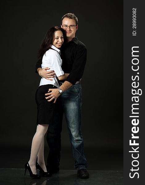 Happy young couple posing in studio on black background