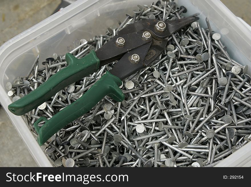 A pair of snips in a bucket of nails. A pair of snips in a bucket of nails