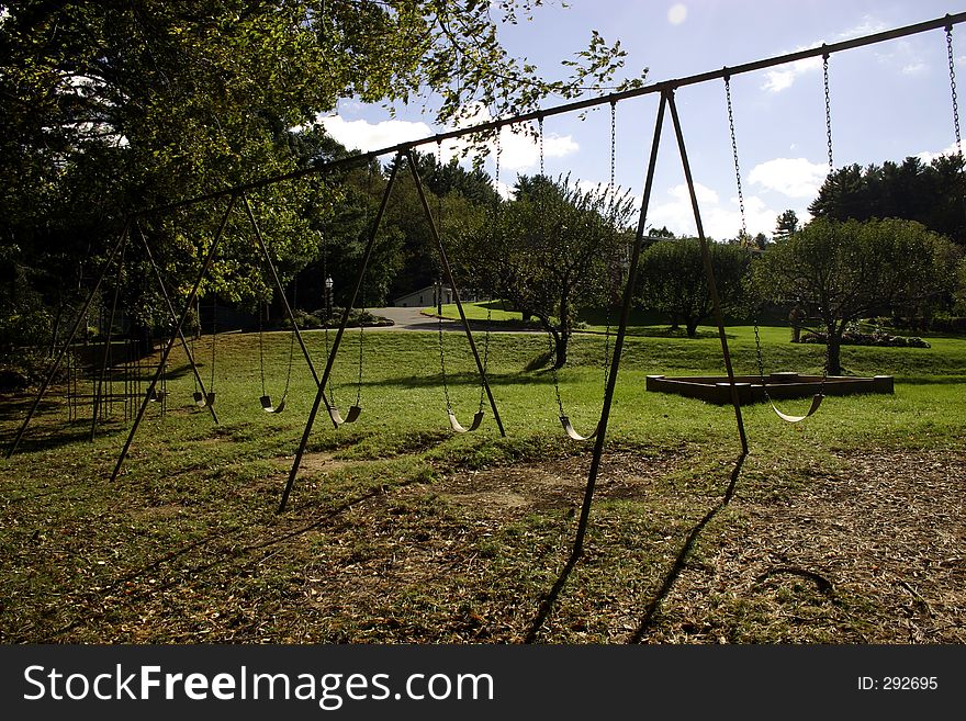 Huge playground swingset situated on beautiful rolling green hillside