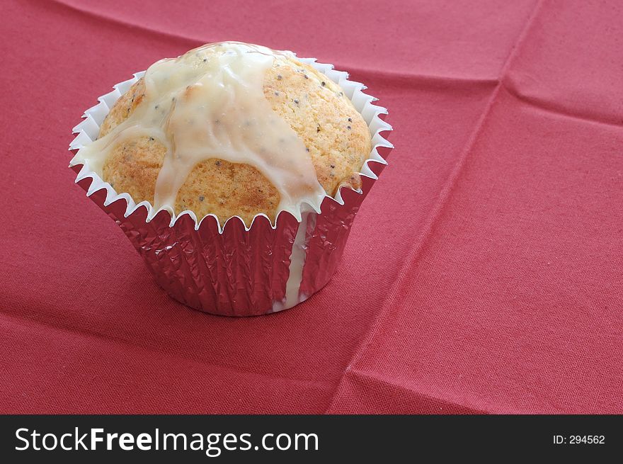 A muffin on a red cloth, still in individual metal baking tin. A muffin on a red cloth, still in individual metal baking tin