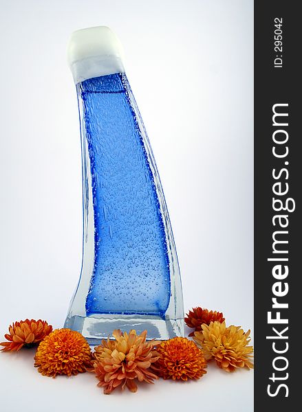 A blue bottle surrounded by orange mums