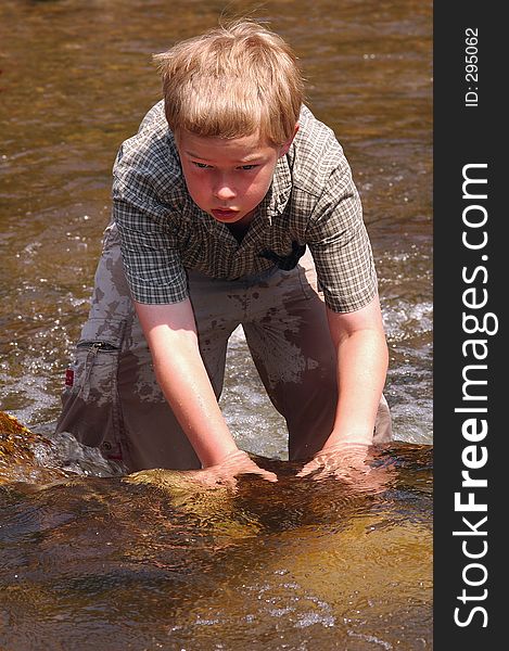 Boy plays in a cool creek on a hot summer day. Boy plays in a cool creek on a hot summer day