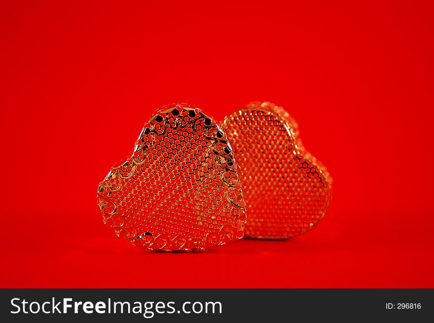 Two golden hearts side by side on a red background.