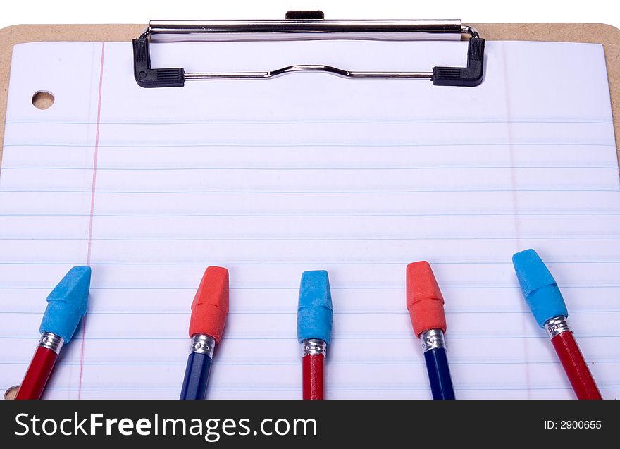 Clipboard with notebook paper, pencils and erasers arranged to provide copy space on paper. Clipboard with notebook paper, pencils and erasers arranged to provide copy space on paper.