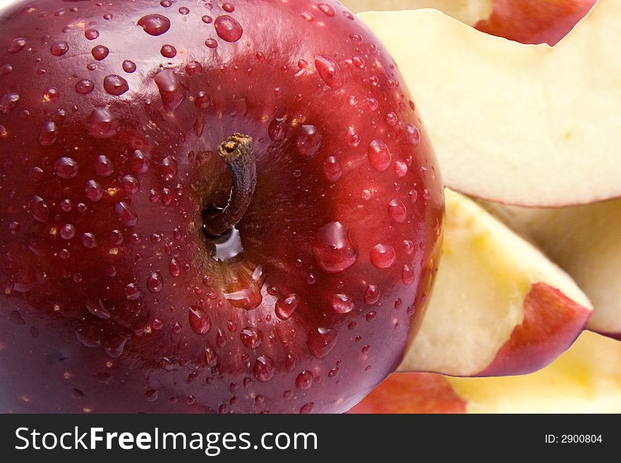 Close-up of a red delicious apple with slices in the background.