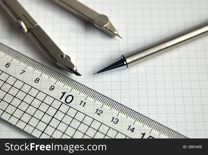 Pencil compass and ruler on white graph paper