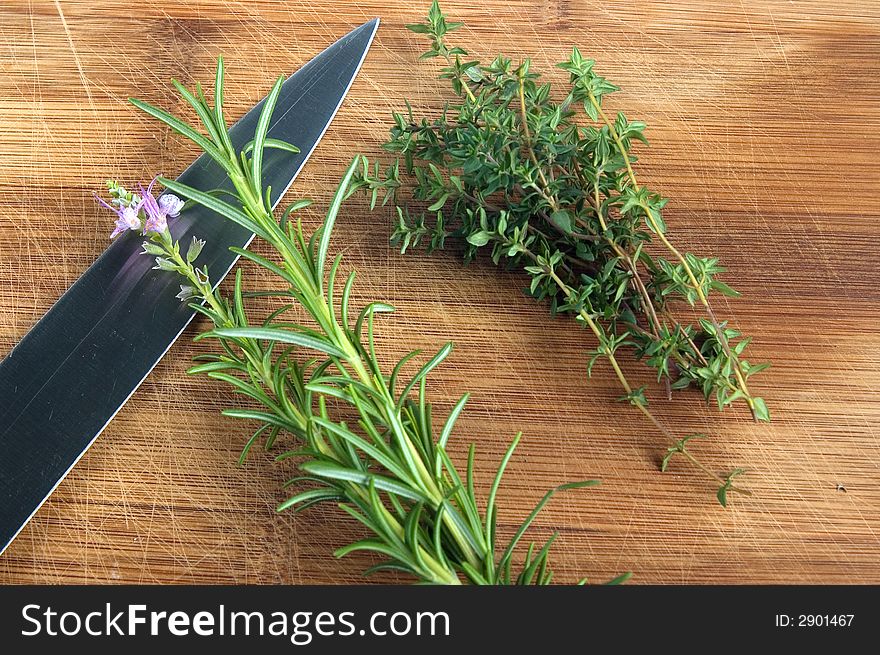 Rosemary and thyme on a chopping board with knife. Rosemary and thyme on a chopping board with knife