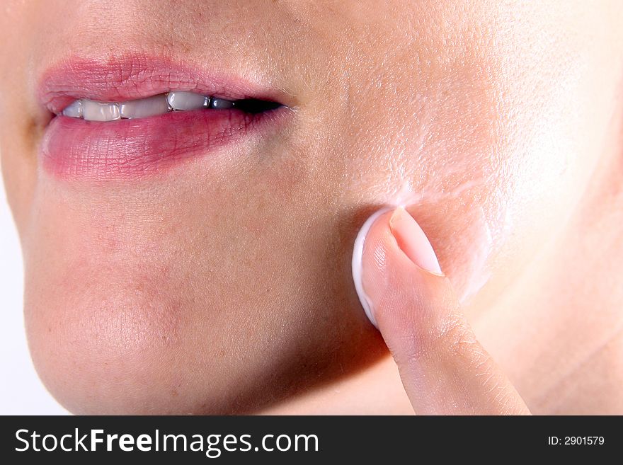 A young woman puts lotion on her face. A young woman puts lotion on her face.