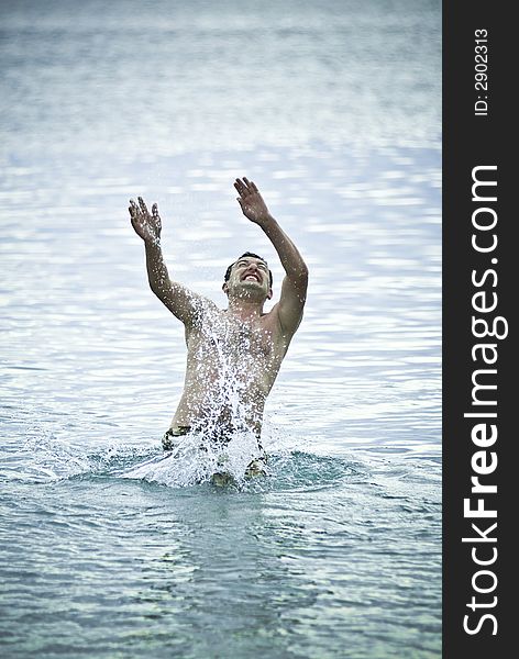 Young man jumping into sea water and preparing to swim