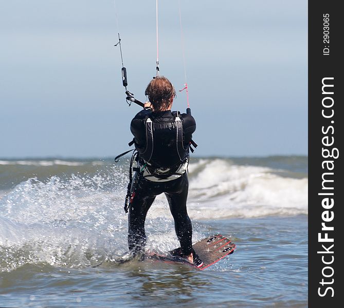 Action shot of a kite boarder at sea water hanging in the waves at high speed. Action shot of a kite boarder at sea water hanging in the waves at high speed.