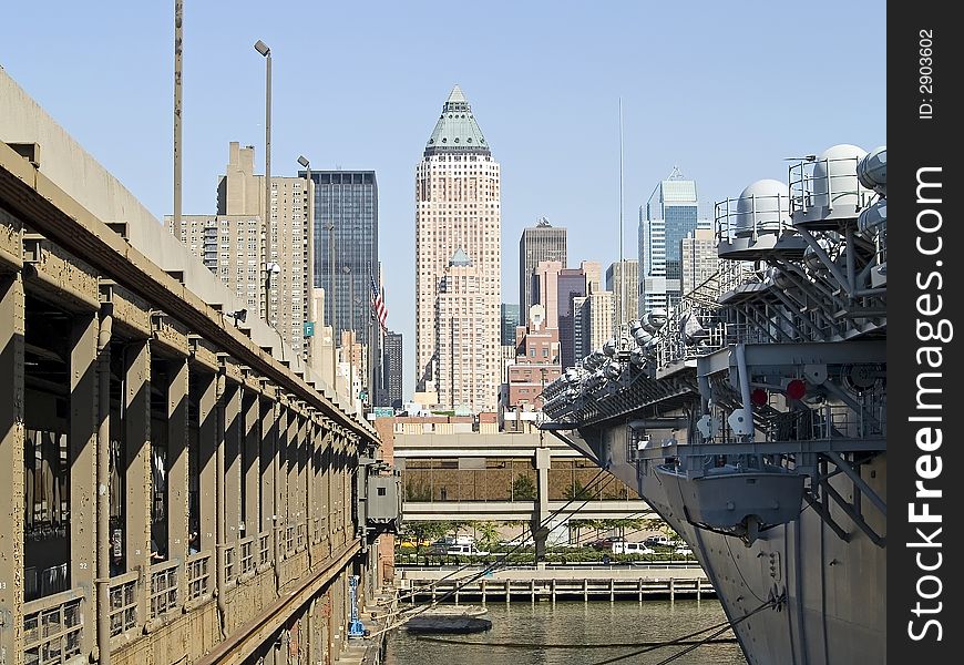 A view of buildings in Manhattan from a pier next to a US Navy aircraft carrier. A view of buildings in Manhattan from a pier next to a US Navy aircraft carrier.