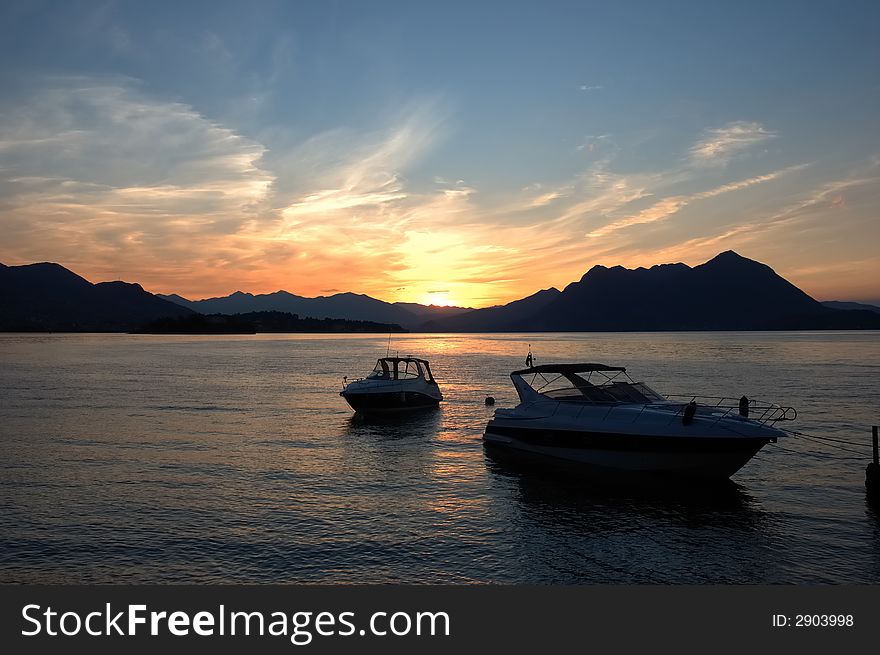 Small yachts anchored in quite lake water before the dawn; Maggiore Lake, Italy. Small yachts anchored in quite lake water before the dawn; Maggiore Lake, Italy.