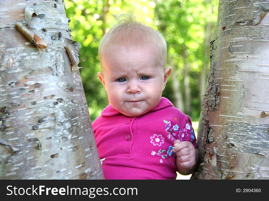 Little Baby Girl posing by a tree in summer