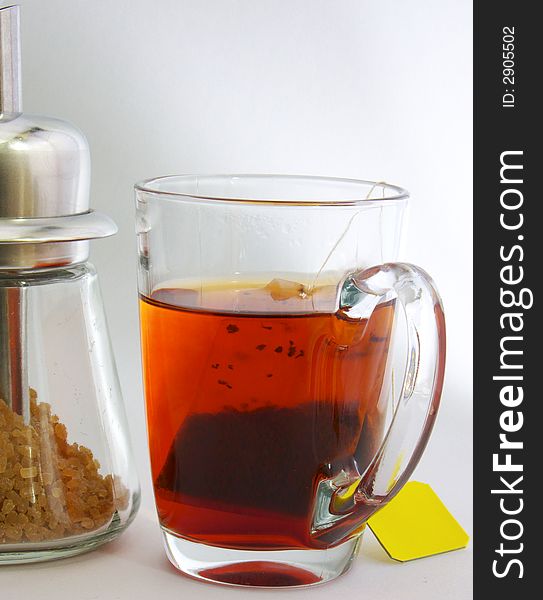 Cup of tea and Sugar-bowl with sugar. In a cup of tea package with a yellow label. In Sugar-bowl - brown sugar.