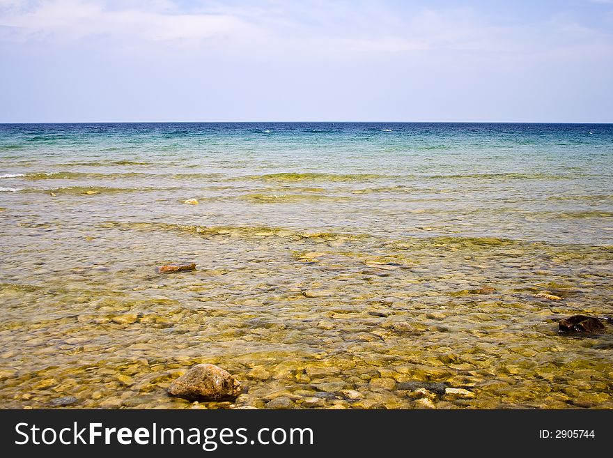 Landscape shot of lake huron on the beach bright blue colors rocks in the foreground. Landscape shot of lake huron on the beach bright blue colors rocks in the foreground