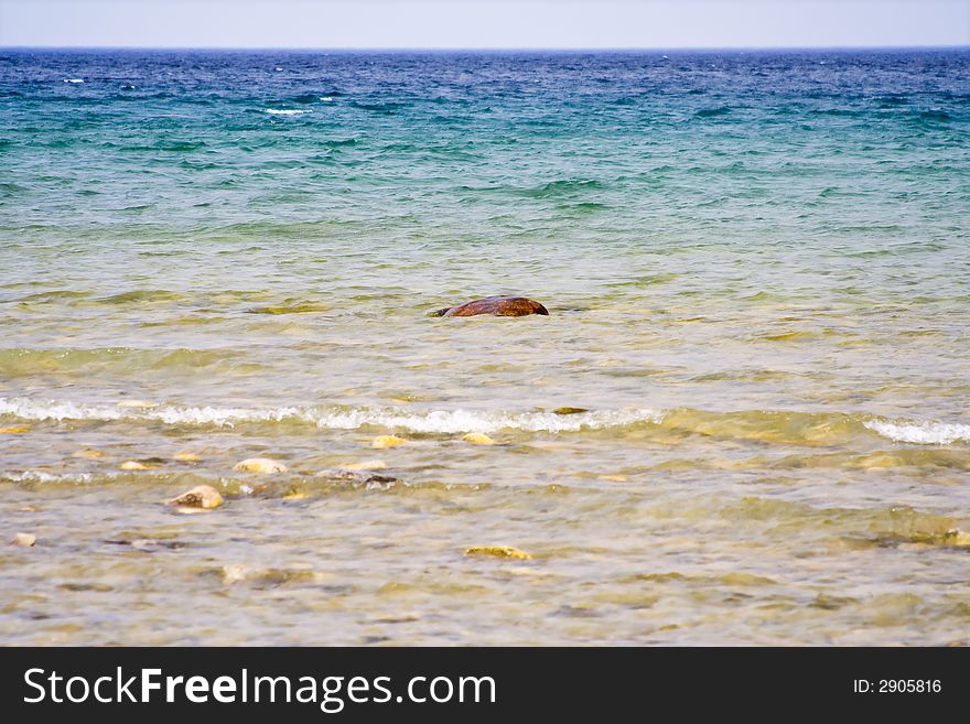 Landscape shot of lake huron on the beach bright blue colors rocks in the foreground. Landscape shot of lake huron on the beach bright blue colors rocks in the foreground