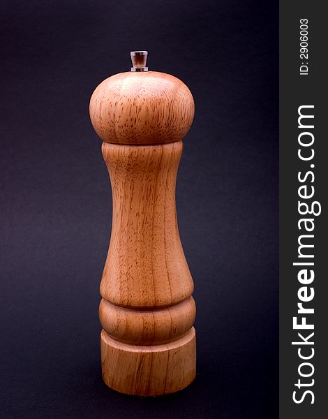 A pepper mill against a black background