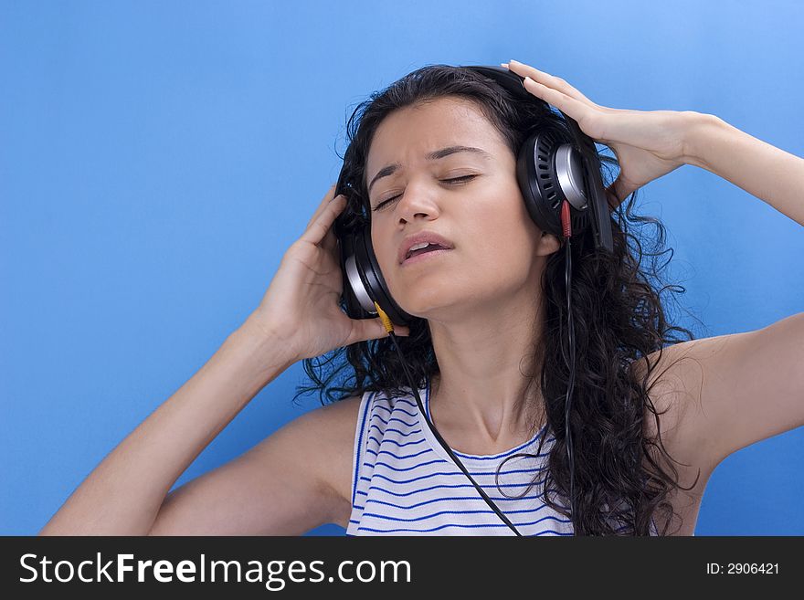 young beautiful girl listening music on blue background