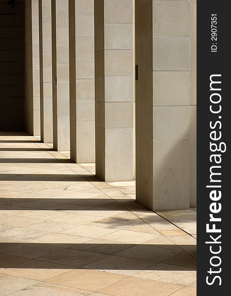 Stone columns lit from the side with long shadows cast upon the ground