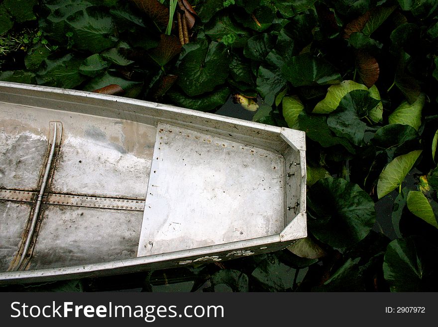 Aluminum canoe resting amidst waterlilies in rural pond. Aluminum canoe resting amidst waterlilies in rural pond