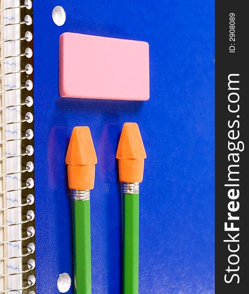 Blue spiral notebook with green pencils and pink eraser. Blue spiral notebook with green pencils and pink eraser