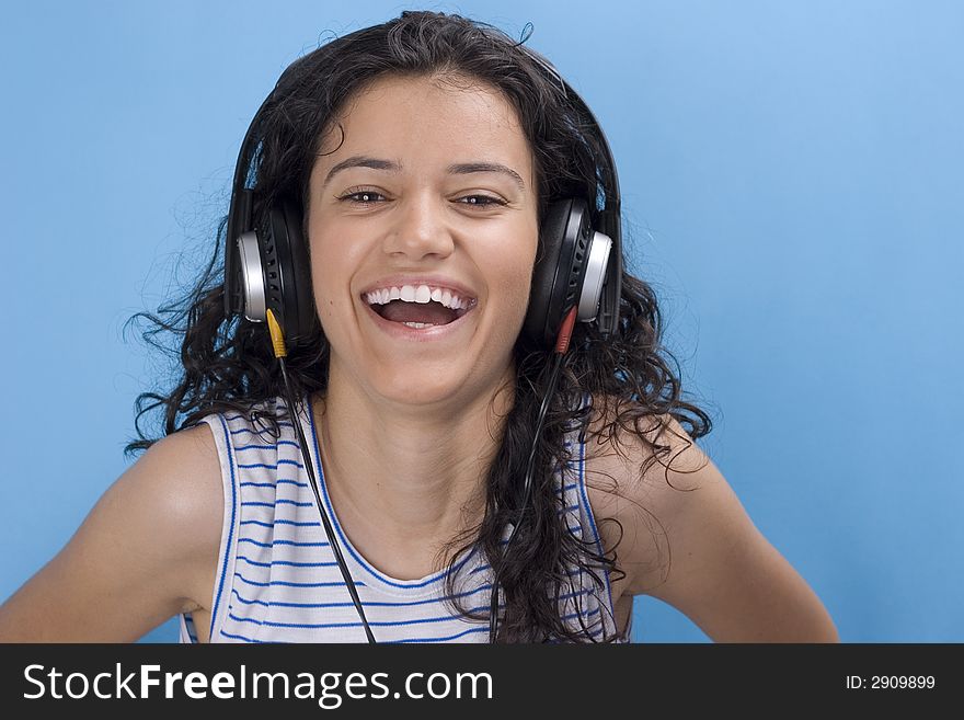Young beautiful girl listening music on blue background
