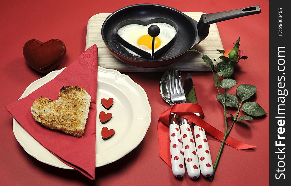 Red theme Valentine breakfast with heart shape egg and toast with love hearts on red background.