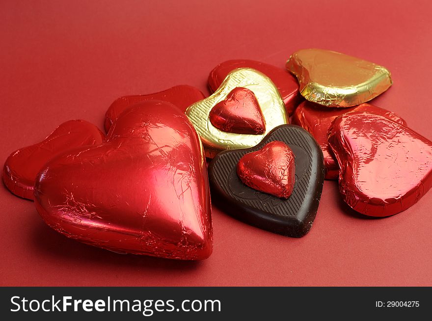 Red and gold wrapped chocolates against a red background for Valentine's Day, Christmas, birthday or someone special. Red and gold wrapped chocolates against a red background for Valentine's Day, Christmas, birthday or someone special.