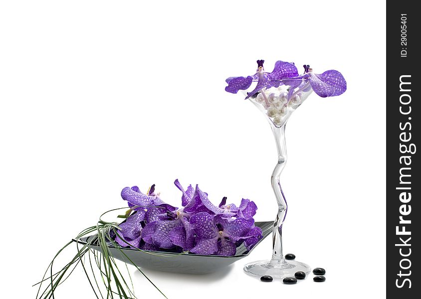 Flowers of orchid Vanda in a composition with grass stems, wineglass and plate, isolated on a white. Flowers of orchid Vanda in a composition with grass stems, wineglass and plate, isolated on a white