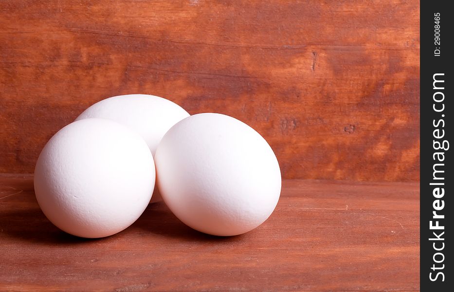 Three white eggs on the wooden background