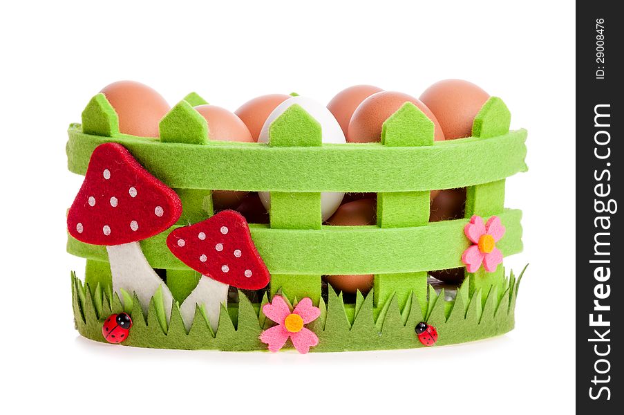 Chicken eggs in the green decorative basket on the white