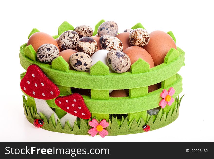 Quail eggs and chicken in green decorative basket on the white