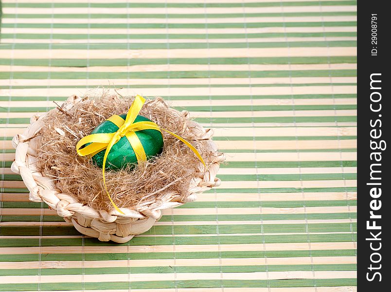 Green Easter egg in a straw hat on the decorative straw