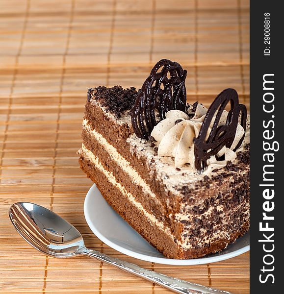 Piece of the cake is decorated with chocolate on the background of decorative straw