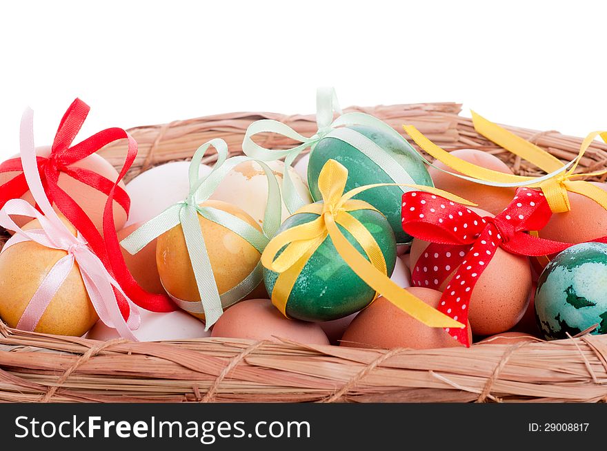 Easter eggs in a straw basket on the white