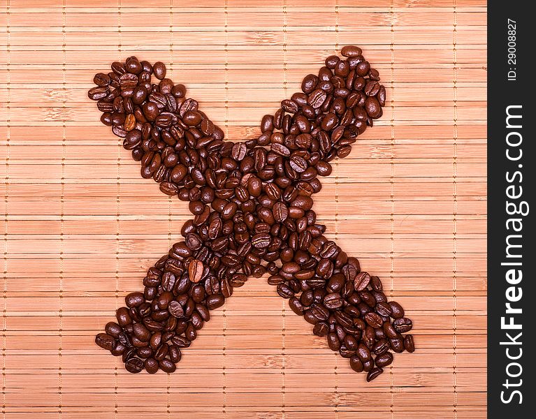 Symbol of the cross is laid grains of coffee on a decorative straw. Symbol of the cross is laid grains of coffee on a decorative straw