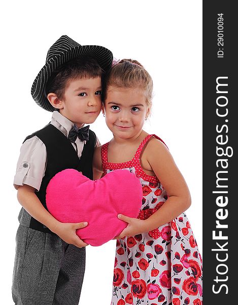 Little boy and girl hug each other and they are holding a big pink heart. Little boy and girl hug each other and they are holding a big pink heart