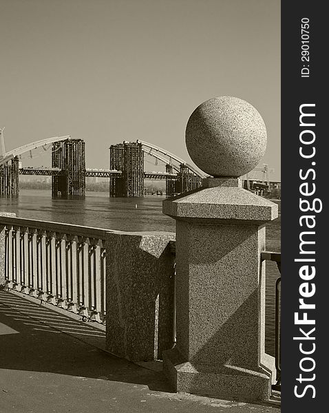 Granite ball on the background of the bridge being built across the River Dnipro in Kiev, Ukraine. Granite ball on the background of the bridge being built across the River Dnipro in Kiev, Ukraine