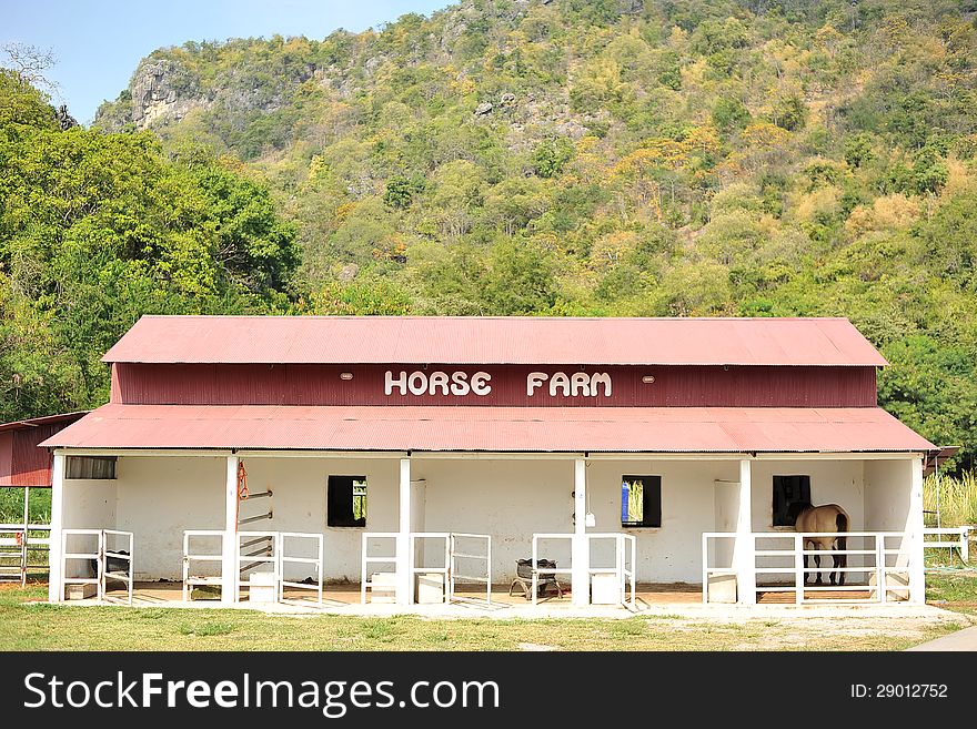 A horse house with a horse in front of a mountain during day time. A horse house with a horse in front of a mountain during day time