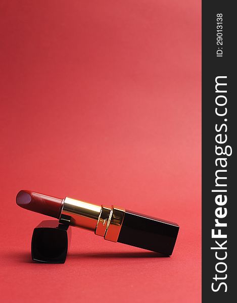 Luxury red lipstick against a red background, vertical with copy space