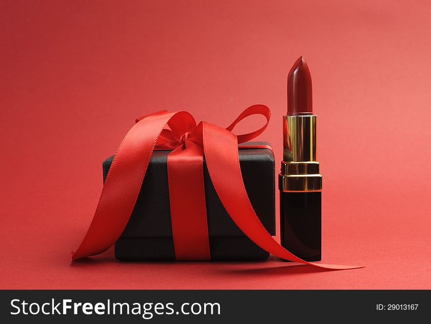 Beautiful luxury red lipstick with black box gift against a red background, for Valentine, Christmas, birthday or special occasion.