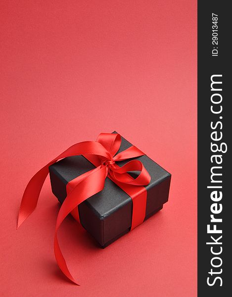 Black box romantic gift with red ribbon, vertical with copy space.