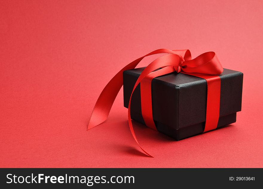 Beautiful Valentine black box gift present with red ribbon bow on a red background. Beautiful Valentine black box gift present with red ribbon bow on a red background.