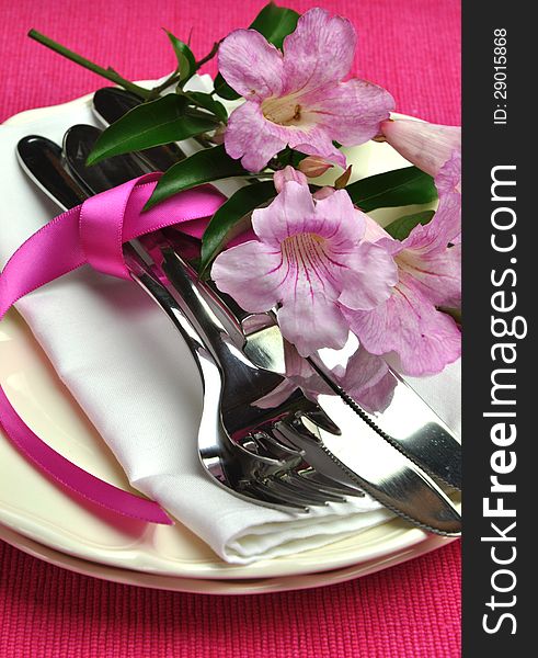 Beautiful silver cutlery, plates and serviette napkins, and pink flowers for a modern twist on traditional table setting elegance. Beautiful silver cutlery, plates and serviette napkins, and pink flowers for a modern twist on traditional table setting elegance.