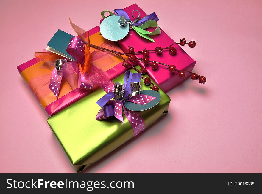 Bright color festive present gifts, in pink and green against a pink background for Christmas, Easter, birthday or Mothers Day holiday events.
