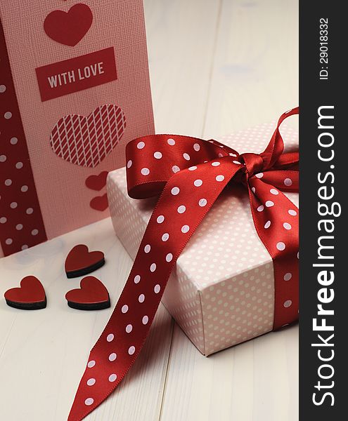 Love theme ft card with pink gift and red polka dot ribbon and hearts. Vertical.