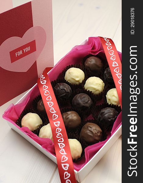 Love theme chocolates with red heart ribbon and pink and red handmade gift card, vertical.