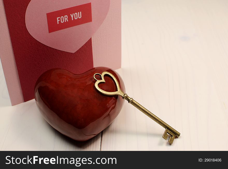 'Key to My Heart' love concept, with gold heart shape key and red heart on white natural wood table with handmade card For You message, for Valentine's Day or for someone special. 'Key to My Heart' love concept, with gold heart shape key and red heart on white natural wood table with handmade card For You message, for Valentine's Day or for someone special.